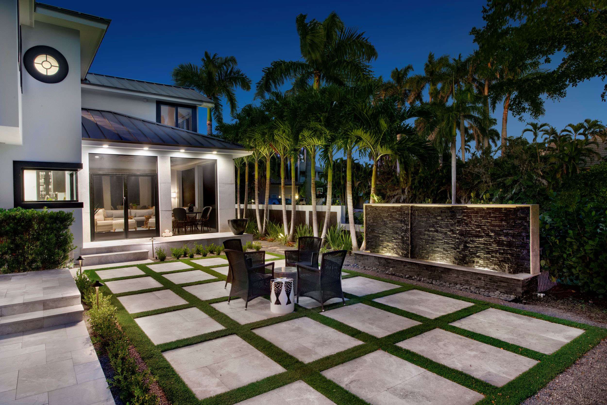 Nighttime view of a Seminole, FL home featuring uplighting on palm trees and illuminated garden pathways.