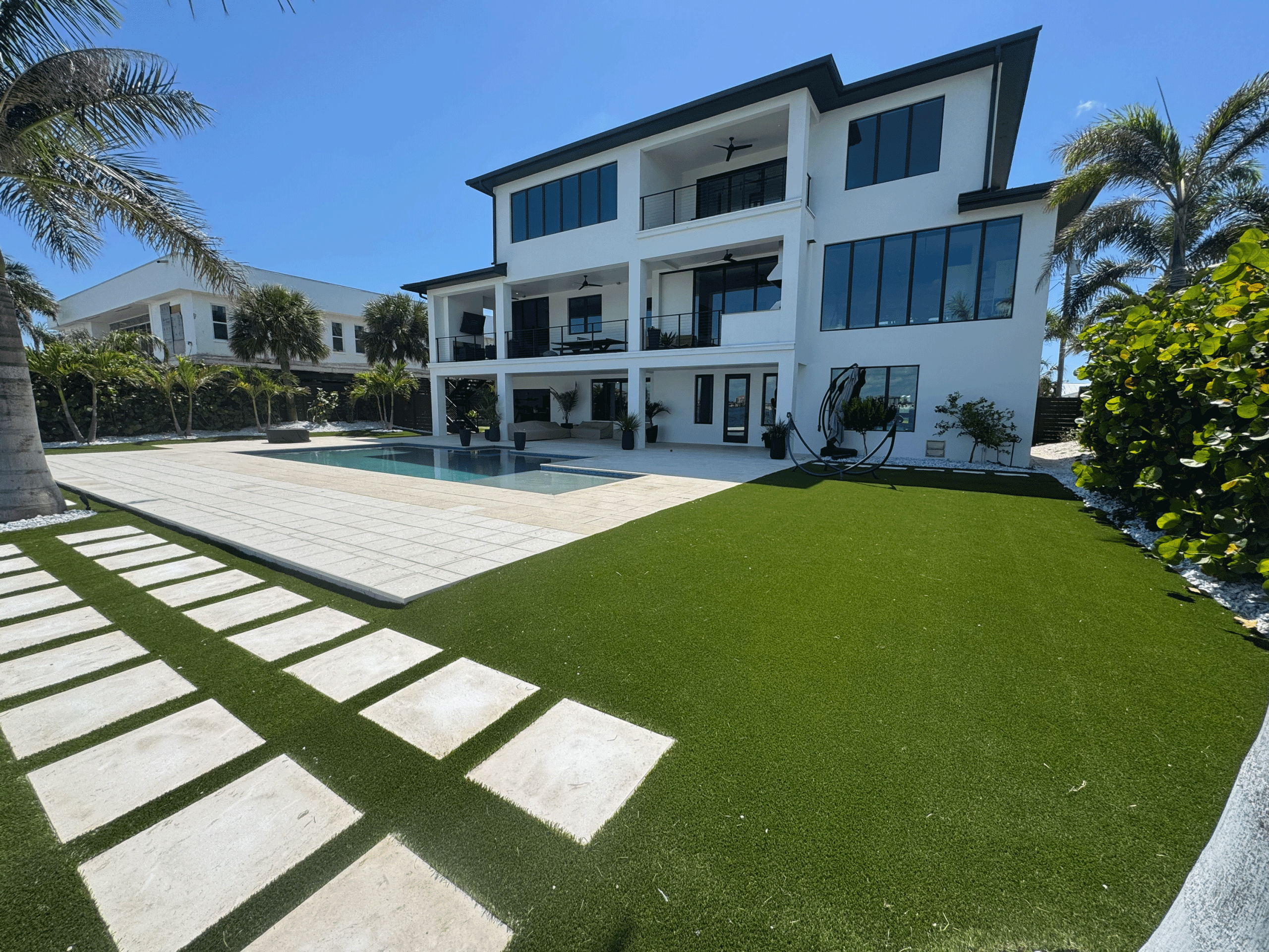 Before and after synthetic turf lawn replacement in a St. Petersburg Florida backyard showing lush green low-maintenance lawn